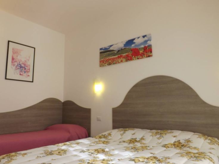 Einfaches Zimmer mit bequemen Betten und schlichten Dekorationen, ideal für einen ruhigen Aufenthalt.