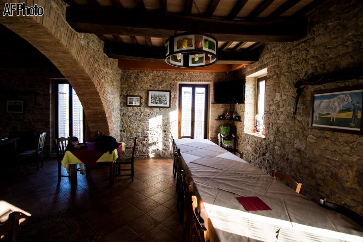 Ein gemütlicher Essraum mit Steinwänden und einem langen Tisch, beleuchtet von natürlichem Licht.