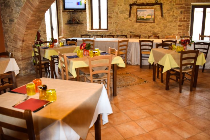 Innenraum eines Restaurants mit angenehmer Atmosphäre, ordentlich gedeckten Tischen und Steinwänden.