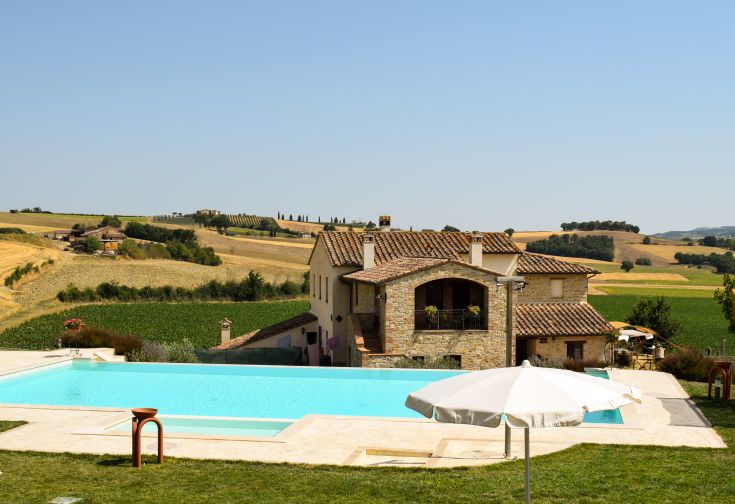 Szene eines Bauernhauses mit einem Pool, umgeben von Grün und Natur.