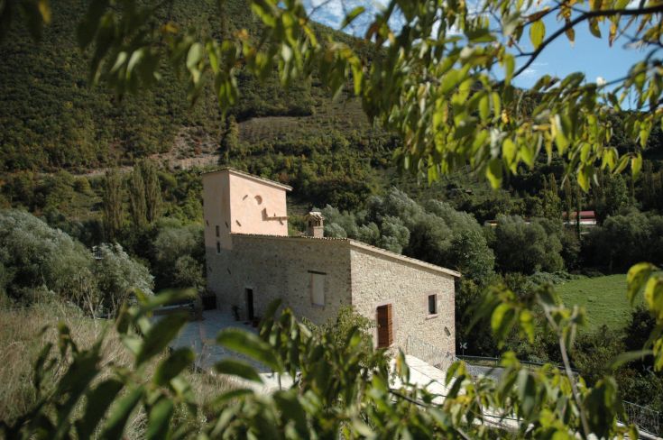 A farmhouse located in a green area, surrounded by trees and plants.