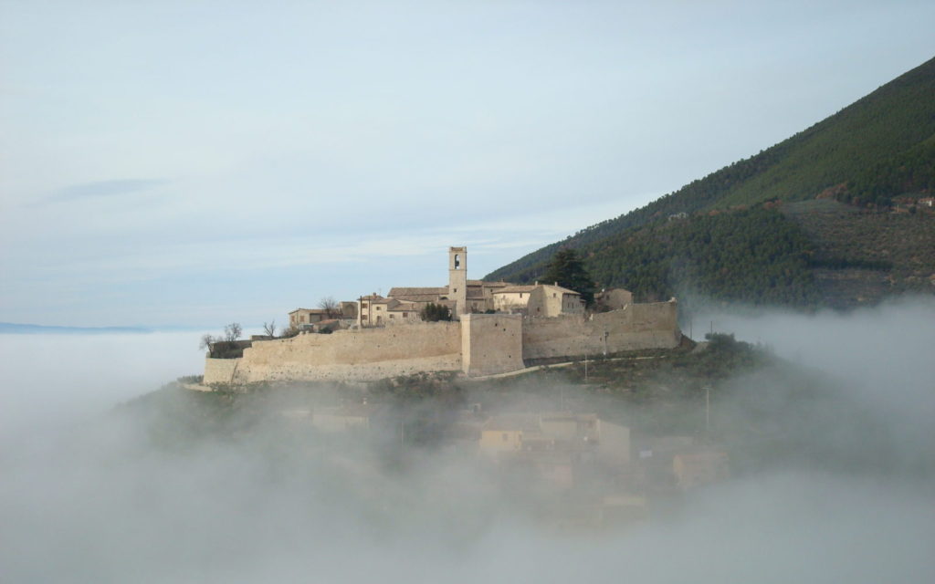Un tranquillo borgo storico avvolto nella nebbia, posto su una collina. Un ambiente sereno per il relax.