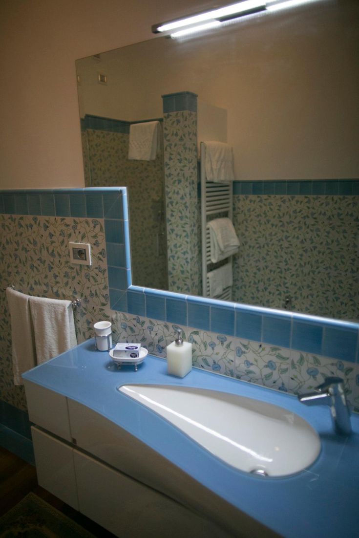 Bathroom with blue tiles and a simple style, featuring a sink and mirror.