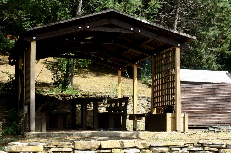 Piccola struttura in legno adibita a pranzo, immersa nel verde e circondata da alberi e vegetazione.