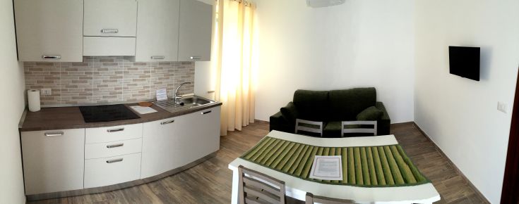 Interno di un moderno appartamento dove si trovano la cucina e il soggiorno, in un'atmosfera luminosa e accogliente.