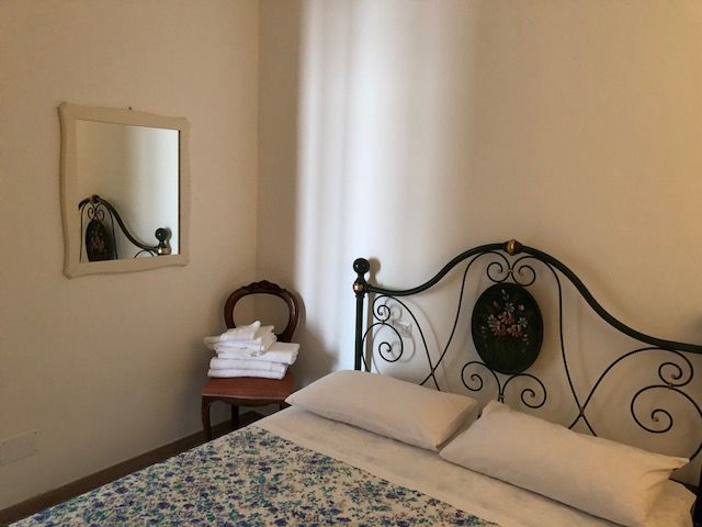 Interno di una camera da letto con un letto a baldacchino e un grande specchio.