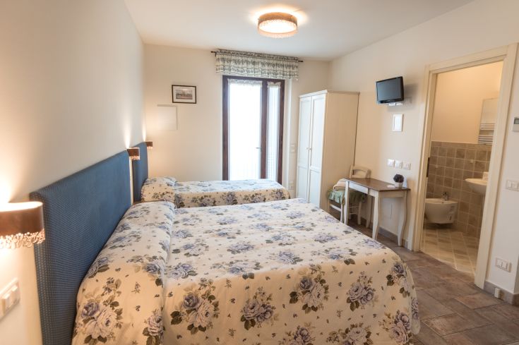 Stanza confortevole con letti singoli, decorazioni floreali e panorama su un giardino. Ideale per un soggiorno tranquillo.