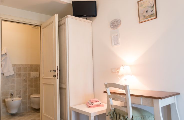 Interno semplice con TV e scrivania, ideale per un soggiorno tranquillo. Include un bagno privato.