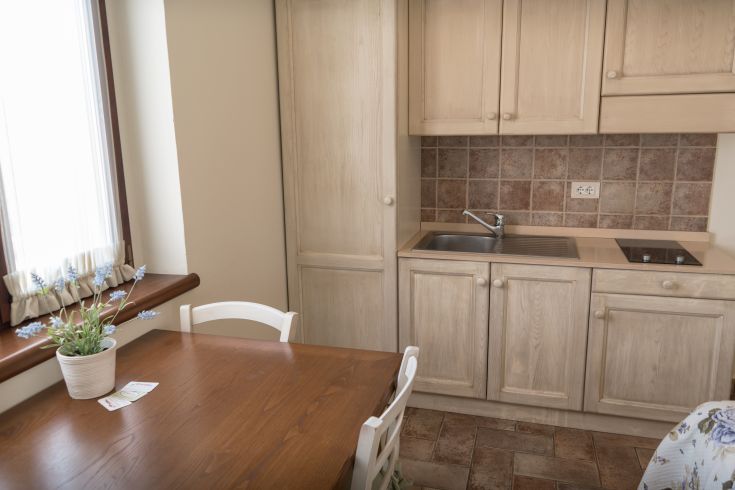 Cucina moderna con dettagli chiari e un tavolo in legno, situata in un ambiente ben illuminato.