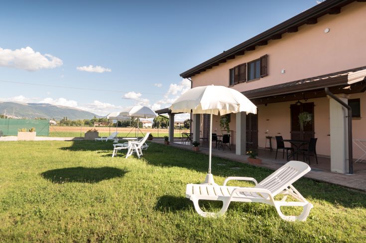 In una località tranquilla dell'Umbria, un'area verde con lettini e ombrelloni offre un accogliente spazio per rilassarsi.