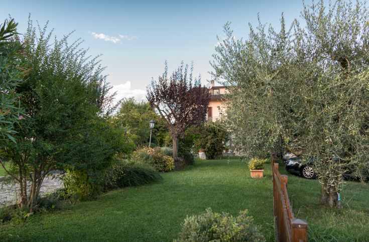 Un giardino curato con alberi e un edificio sullo sfondo, ottimo per godere della natura.