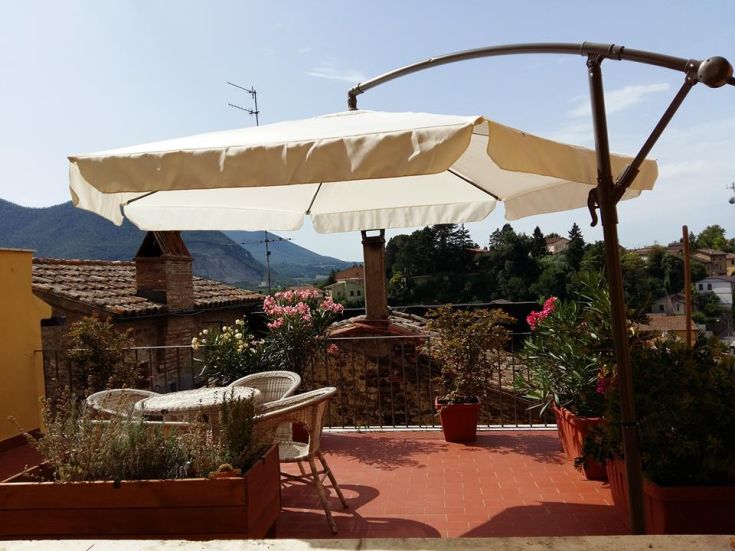 Eine Terrasse mit Pflanzen, Stühlen und einem Sonnenschirm, ideal für Momente im Freien.