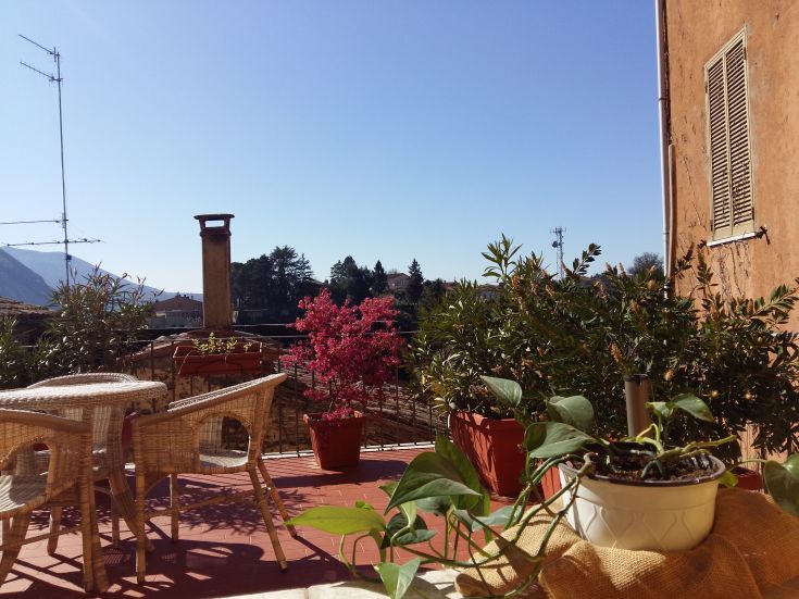 Eine helle Terrasse mit Pflanzen, die auf ein antikes umbrisches Dorf blickt.