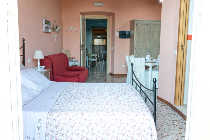 Ein einfacher Aufenthalt mit einem Doppelbett und einem Entspannungsbereich in einem historischen umbrischen Dorf.