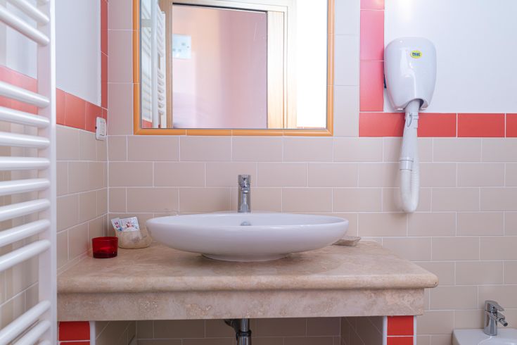 Ein einfaches Badezimmer mit einem modernen Waschbecken und Spiegel, ideal für einen einladenden Raum.