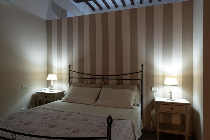 Helle Zimmer mit gestreiften Wänden, bequemen Betten und warmer Beleuchtung. Perfekt für einen ruhigen Aufenthalt.