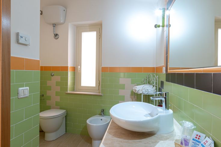 Moderne Badezimmer mit grünen und orangefarbenen Tönen, stilvollen Sanitäranlagen und einem eleganten Waschbecken.