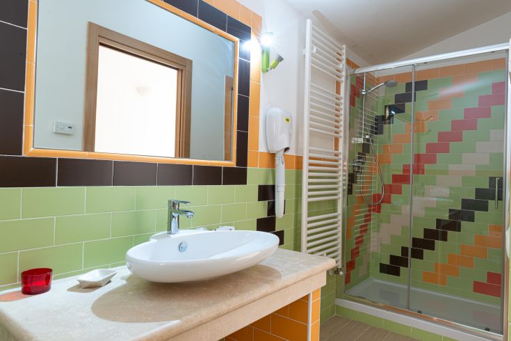 Modernes Bad mit bunten Fliesen und einem stilvollen Waschbecken. Der Raum wirkt einladend und lebhaft.