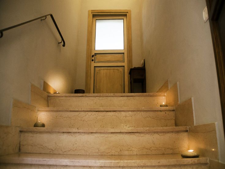 Steintreppe mit sanfter Beleuchtung, die zu einem hellen Holzeingang führt und eine einladende Atmosphäre schafft.