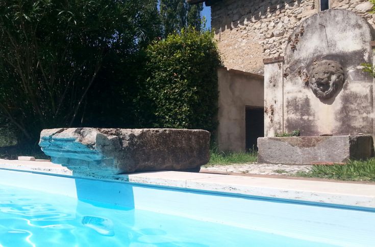 A view of a pool surrounded by ancient structures in a green Umbrian setting.