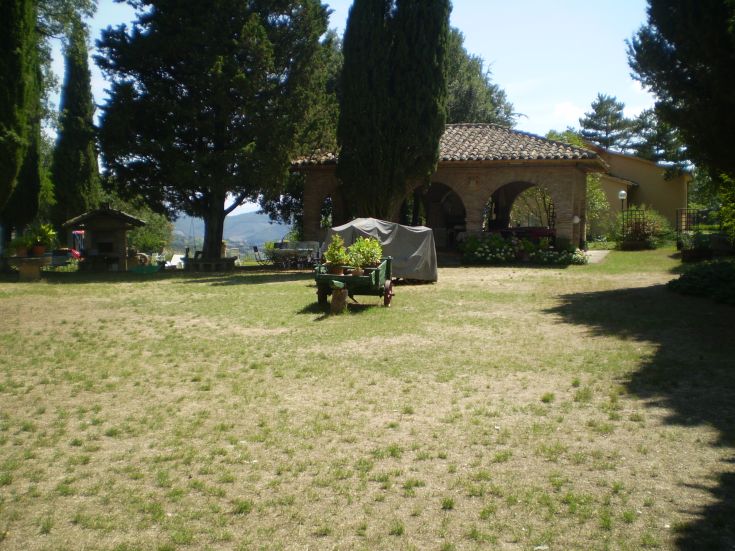 Eine ruhige Landschaft mit einem typischen umbrischen Haus und einem gut gepflegten Garten.