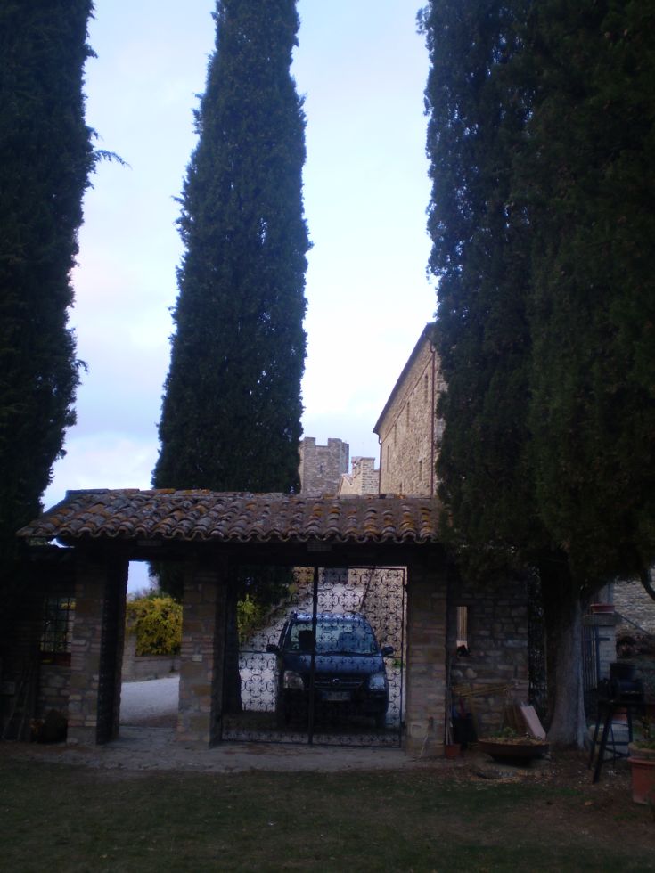 Elegante Steintor-Szene mit einem geparkten Auto, umgeben von hohen Zypressen.