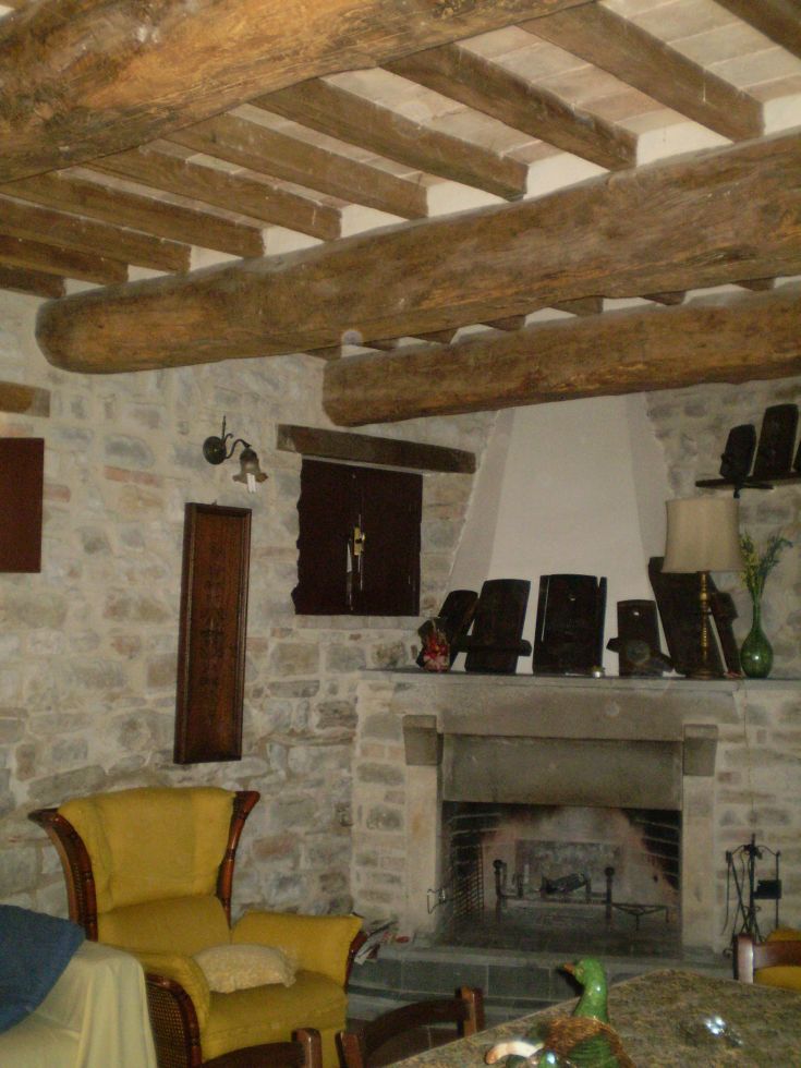 Einfaches Interieur mit Holzbalken und einem Steinkamin, praktisch eingerichtet.