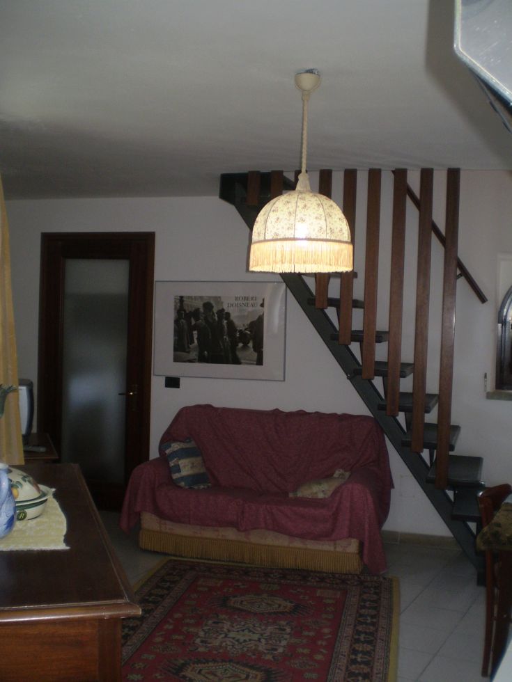 Ein gut eingerichtetes Interieur mit einem bequemen Sofa, einem schlichten Kronleuchter und Holztreppen.