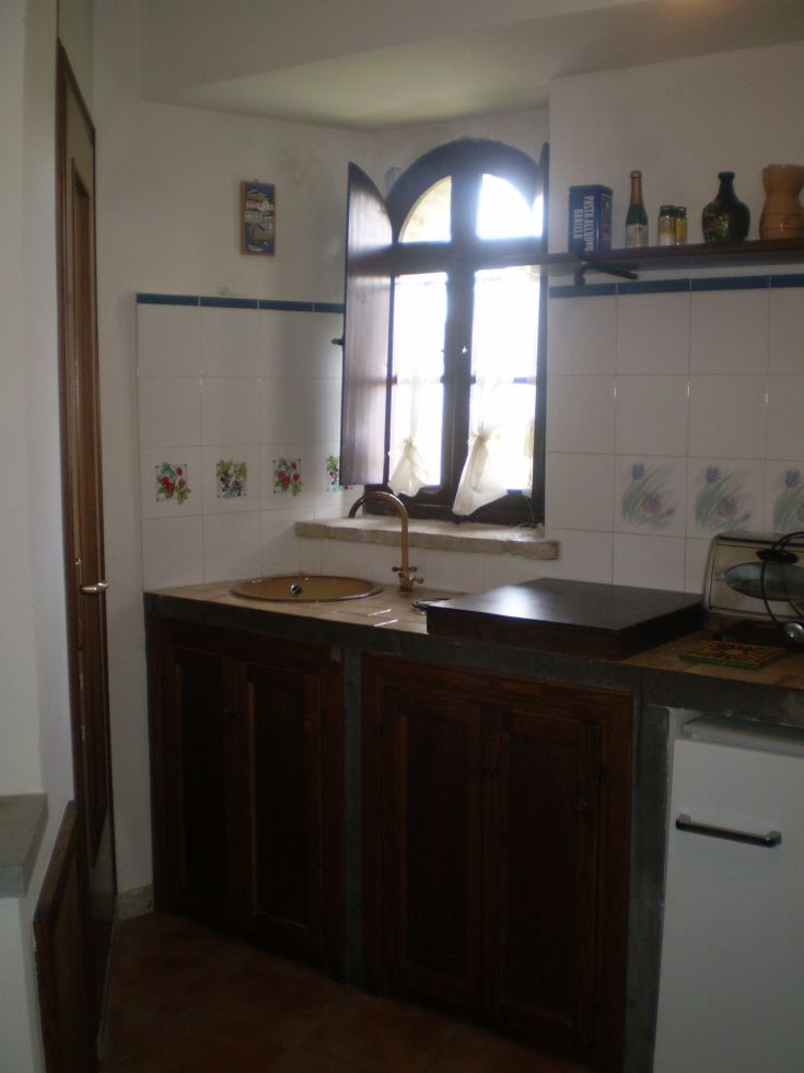 Gemütliche Küche, die mit Holz eingerichtet ist und über ein Fenster für natürliches Licht verfügt.