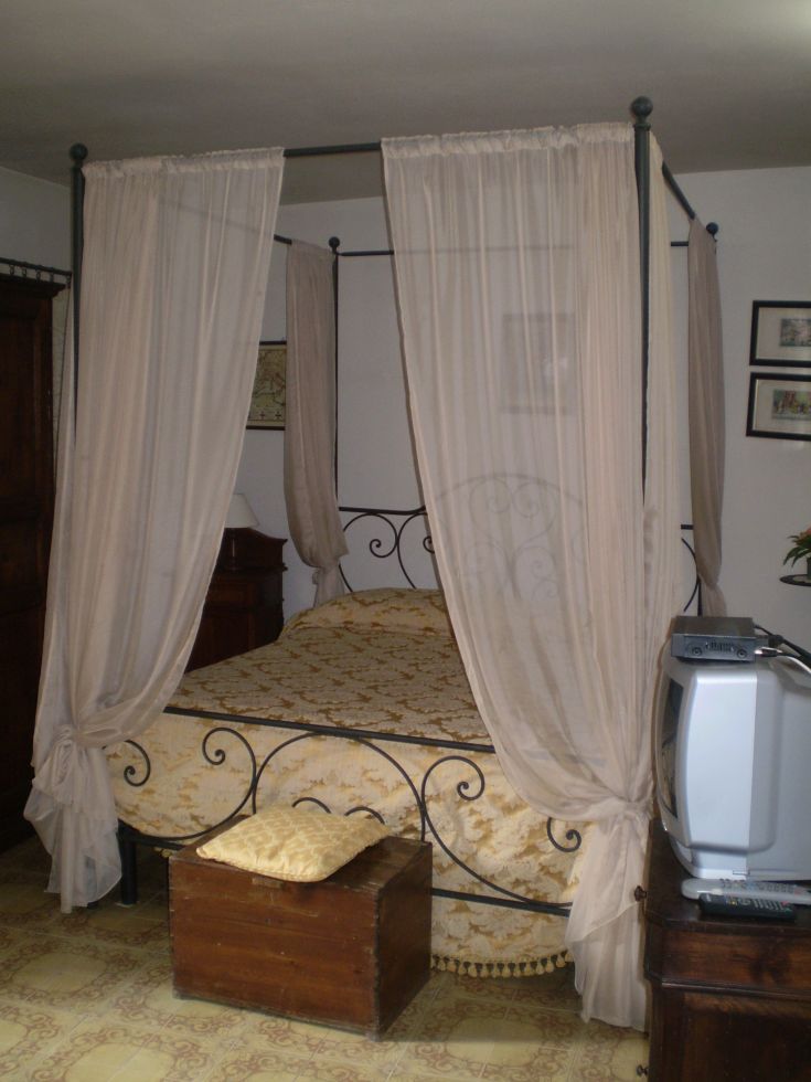 Gemütliches Zimmer mit einem Himmelbett und traditioneller Einrichtung, warm und detailverliebt.