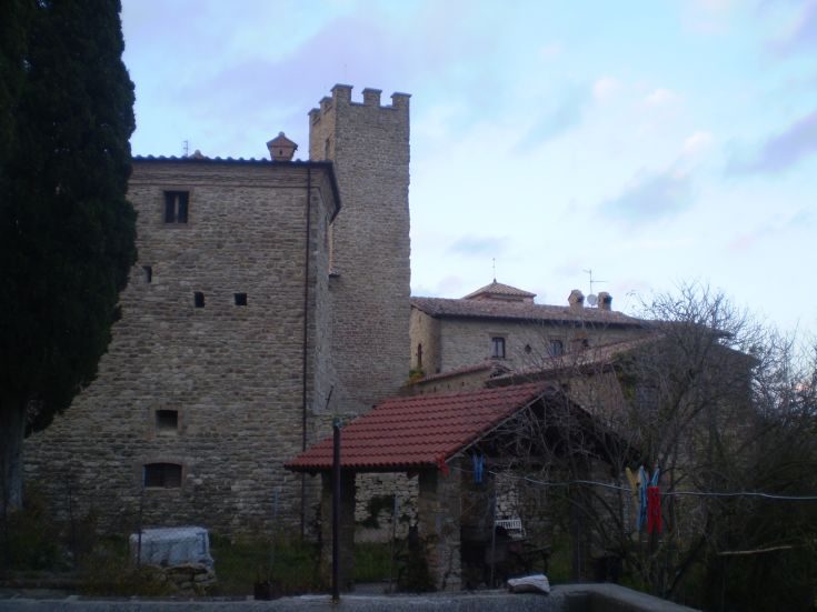 Eine Szene eines antiken Steingebäudes mit Türmen und schrägen Dächern, umgeben von Grün.