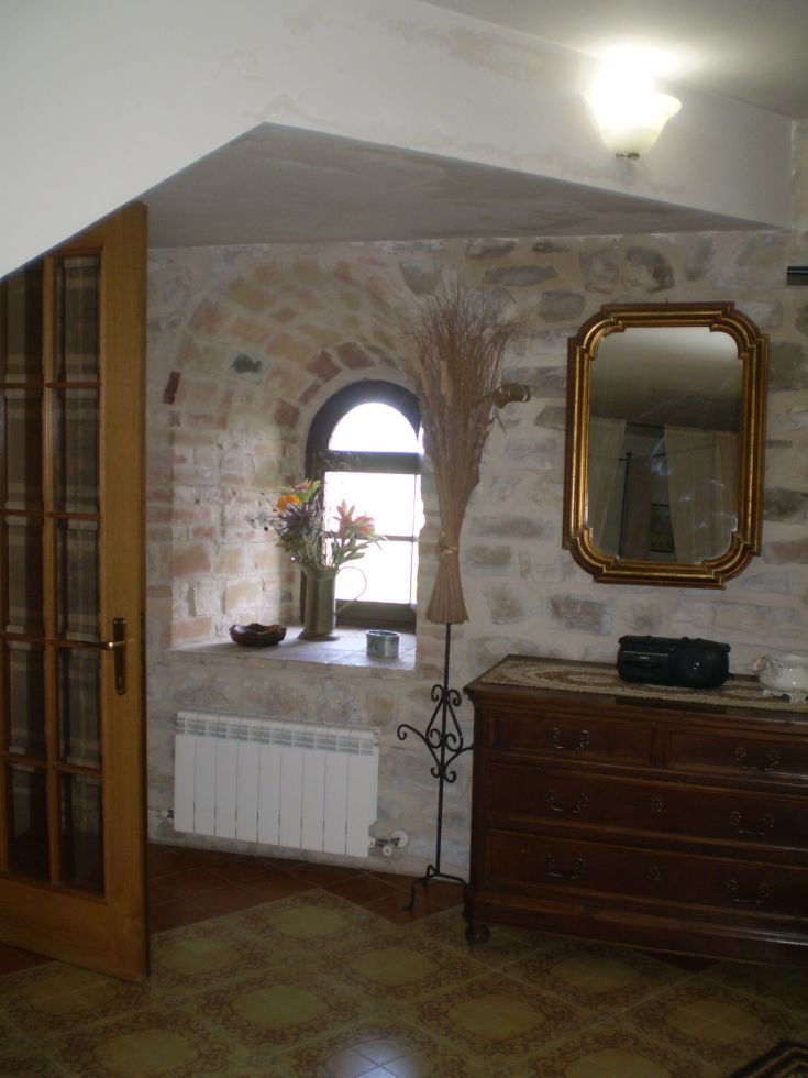 Gemütlicher Raum mit Steinmauern und schlichten Dekorationen.