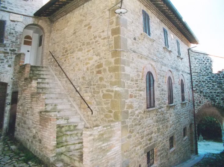 Die Fassade eines Steingebäudes zeigt Außentreppen und rechteckige Fenster.