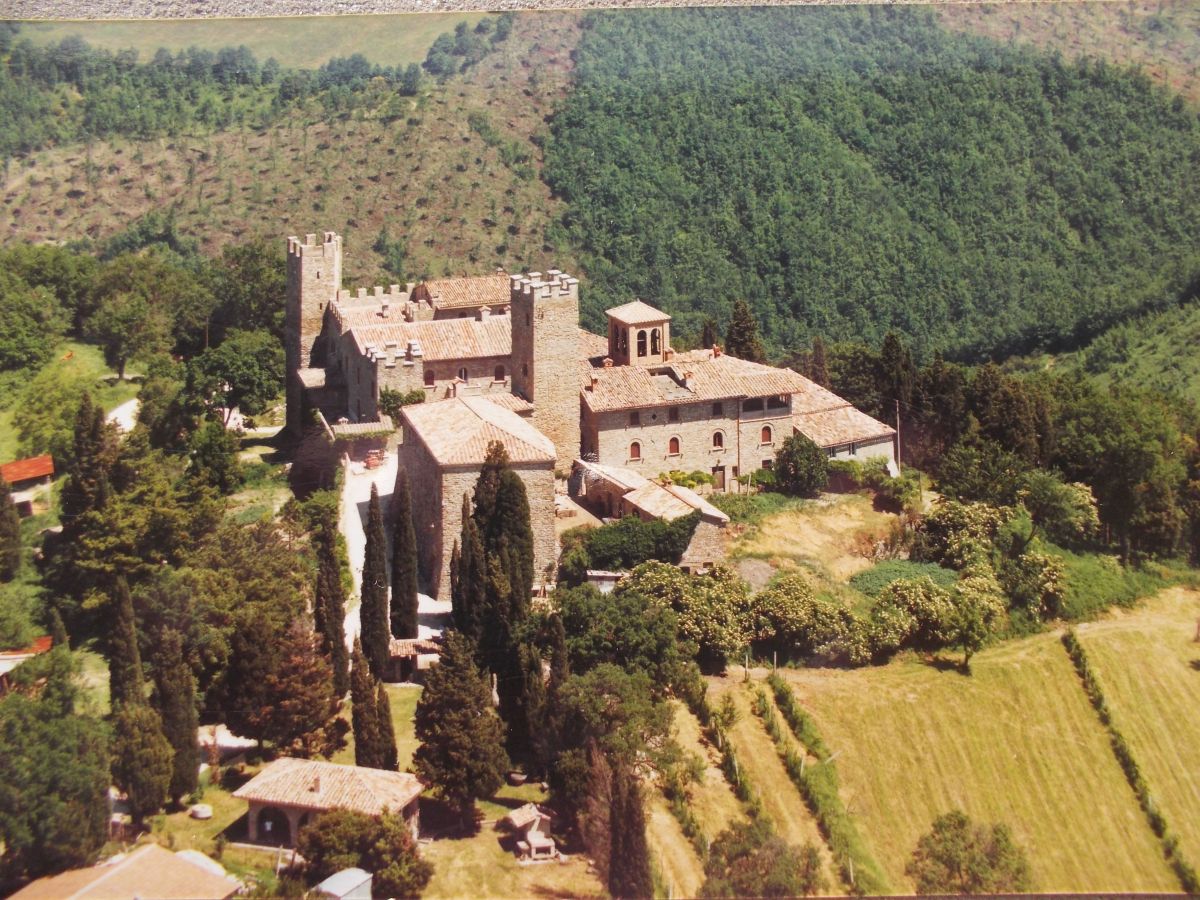 Un edificio circondato da vegetazione verde e campi, adatto per camminate nella natura.