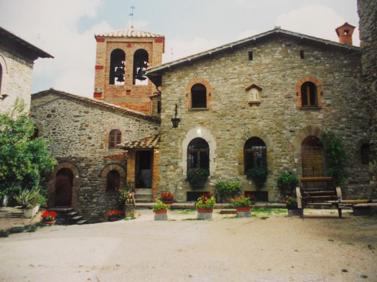 Ein charmantes Steindorf, geschmückt mit bunten Blumen und mit einem Glockenturm.