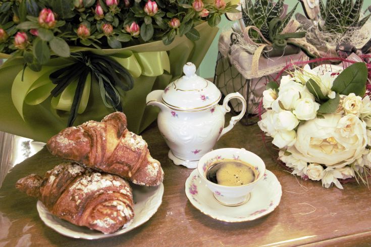 Une table dressée avec des croissants et du café, accompagnée de fleurs fraîches, idéale pour un petit-déjeuner tranquille.