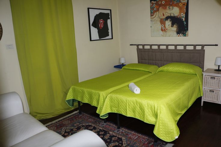 Chambre confortable avec des lits verts, une lumière douce et une décoration simple.