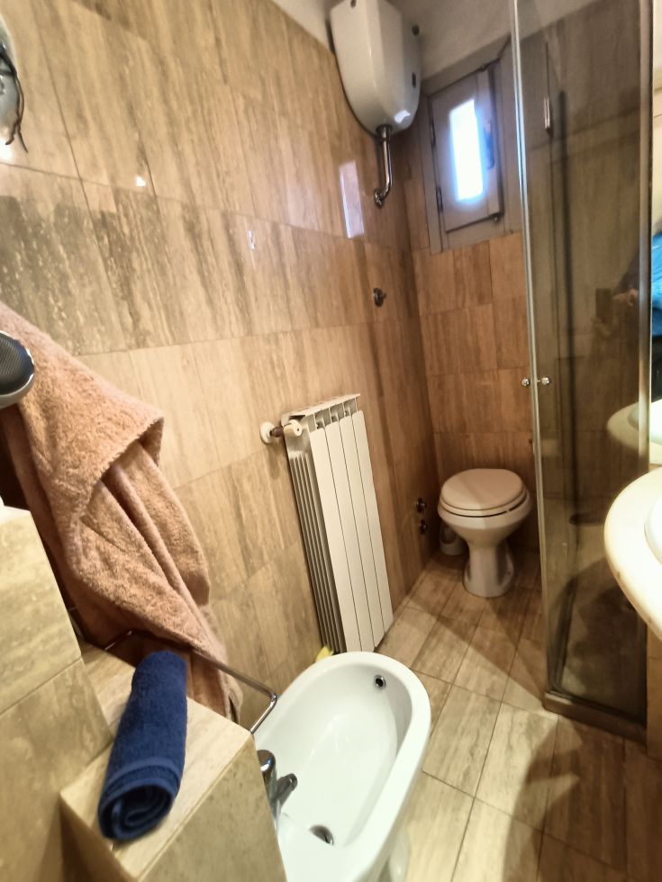 Salle de bain élégante avec des carreaux en pierre, une douche en verre et des éléments fonctionnels.