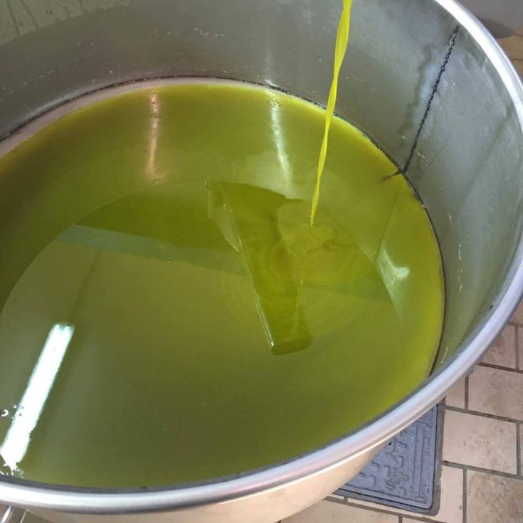 Olio d'oliva di alta qualità, con una tonalità verde intenso, pronto per l'imbottigliamento.