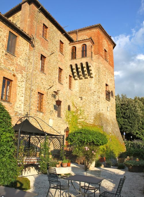 Medieval building surrounded by nature, featuring gardens and surrounding greenery.