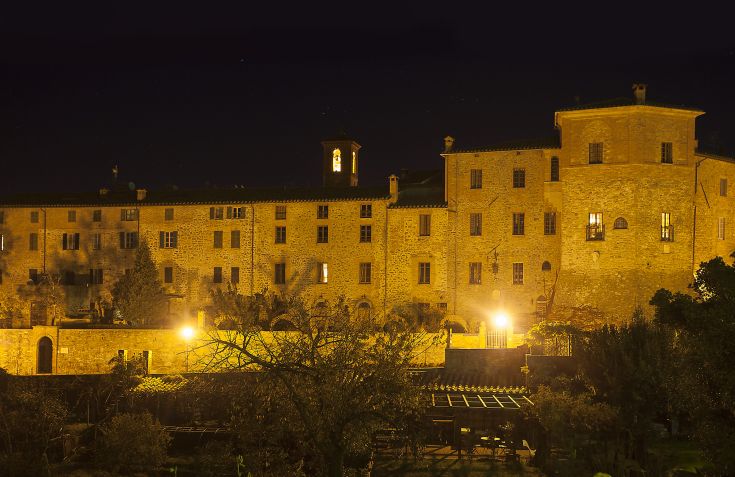 Ein historisches Gebäude, das nachts beleuchtet ist und in der Ruhe der umbrischen Landschaft liegt.