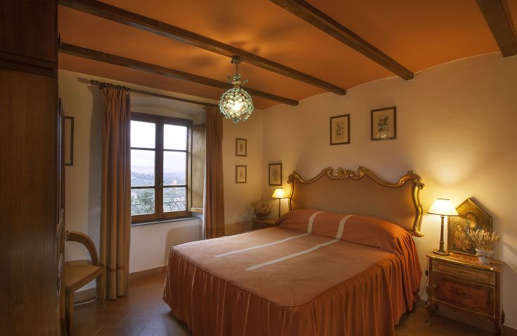 Einfache und helle Zimmer mit Holzbetten und Blick auf die umbrische Landschaft.