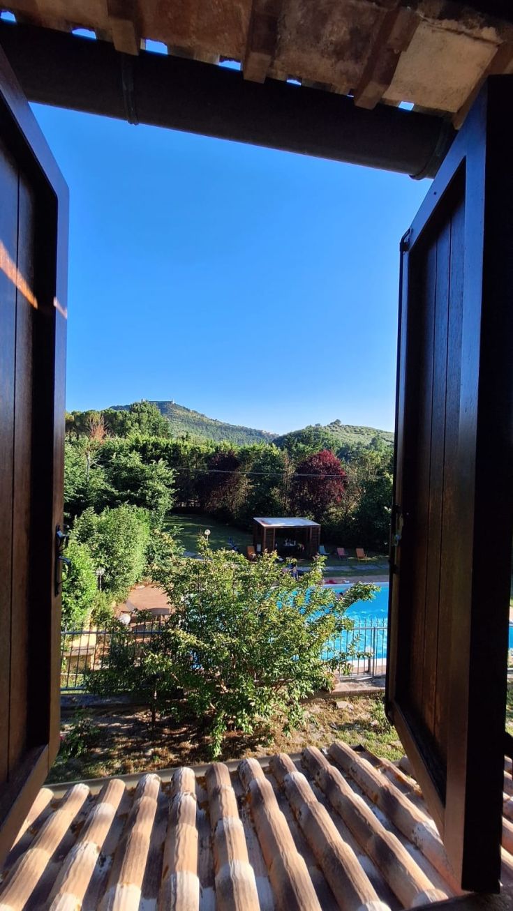 Panorama sulla piscina e il giardino dal soggiorno di un casale. Un ambiente tranquillo immerso nella natura.