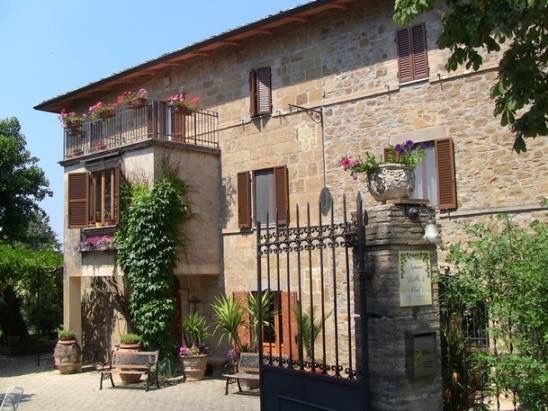 Un edificio ristrutturato, immerso nella natura umbra, circondato da un giardino ben curato.