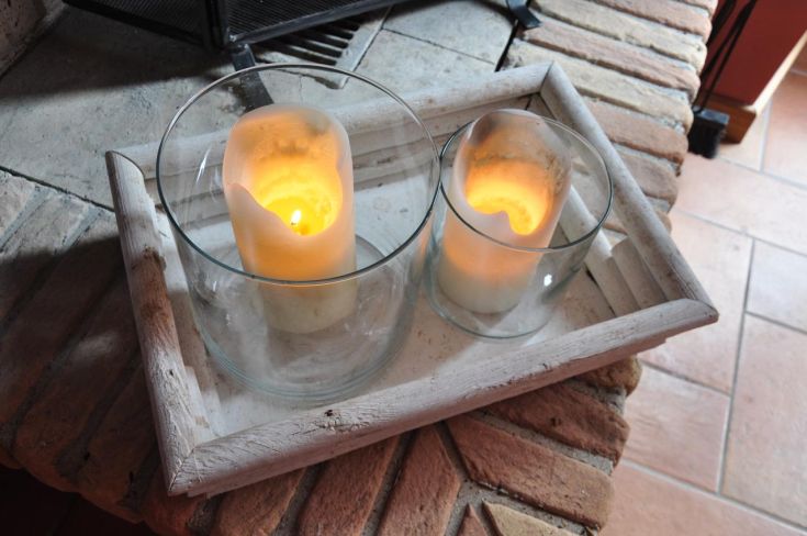 Lit candles in a simple holder on a stone table.