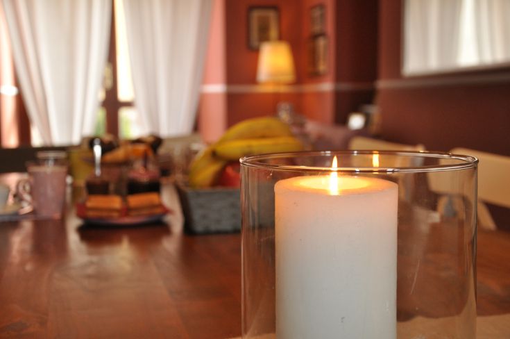 A warm environment with a lit candle and fresh fruit arranged on a table.
