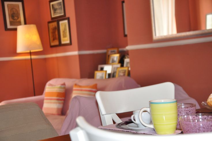 A cozy living room with a beautifully set table and colorful walls.