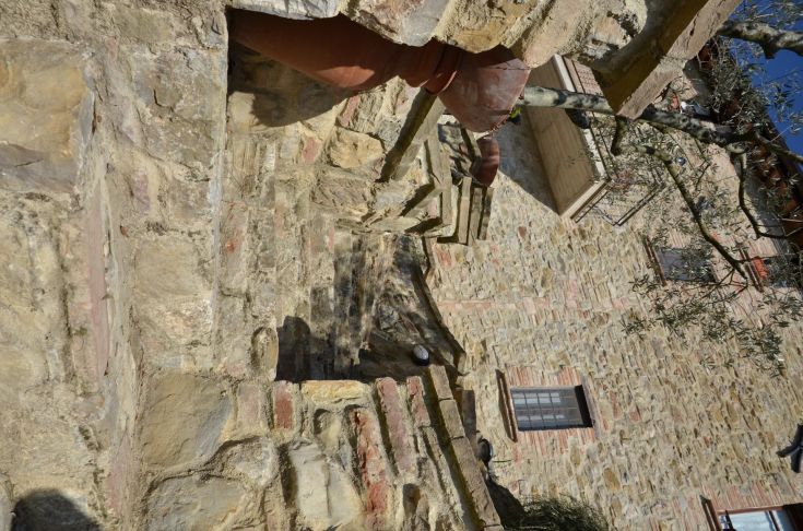 A simple, characteristic stone corner surrounded by greenery in Umbria.