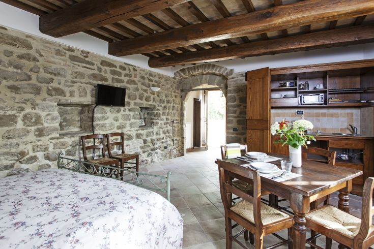 Accogliente agriturismo con muri in pietra, angolo cucina, tavolo da pranzo e panorama naturale.