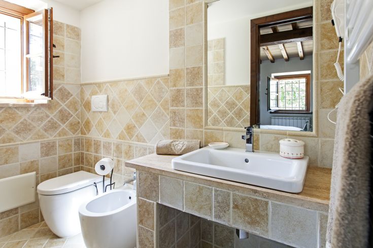 Bagno luminoso e moderno, caratterizzato da piastrelle in pietra e dettagli essenziali.